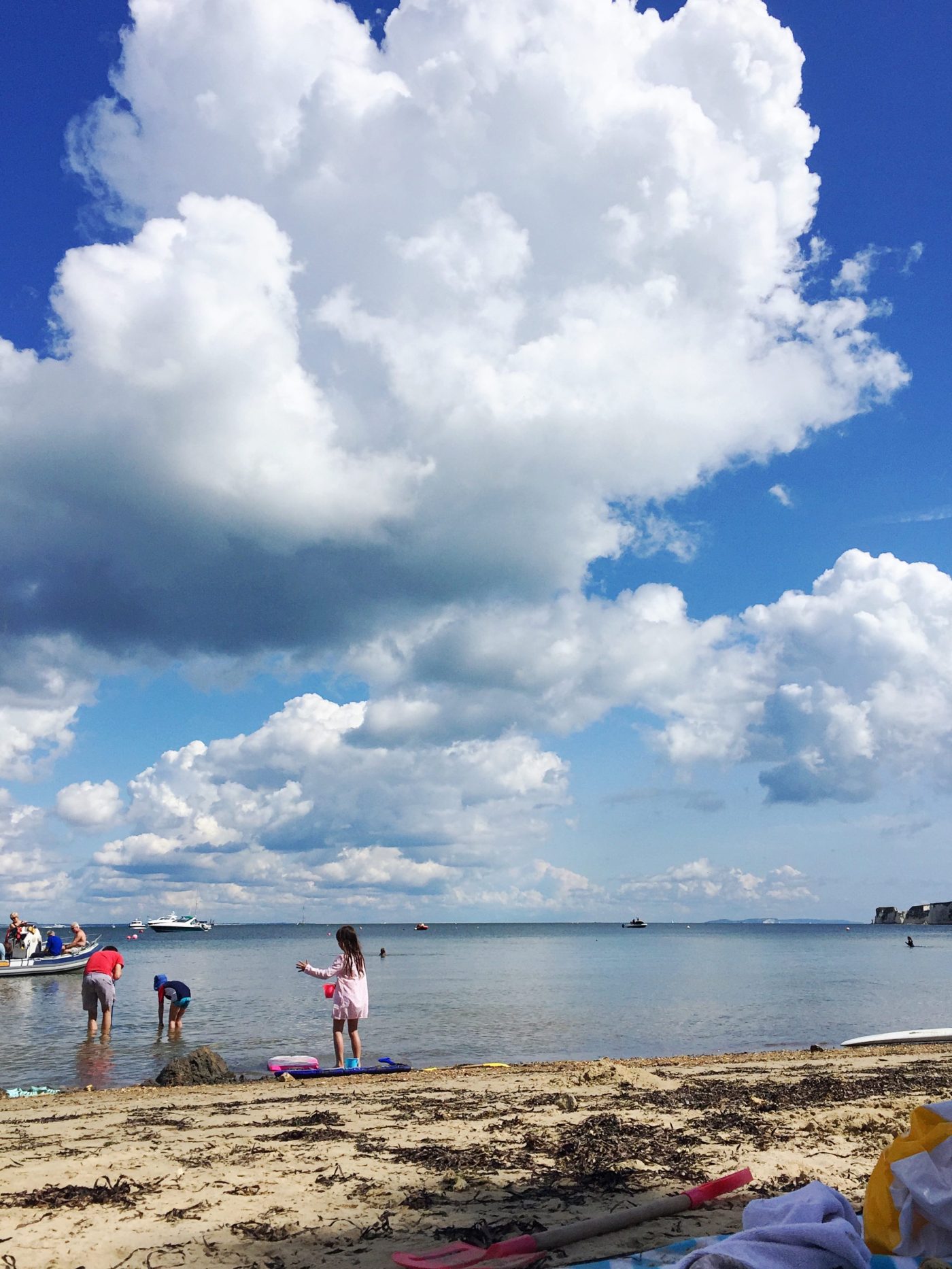 Children play on the beach under a blue sky